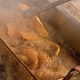 Tongs reaching into boiling deep fryer